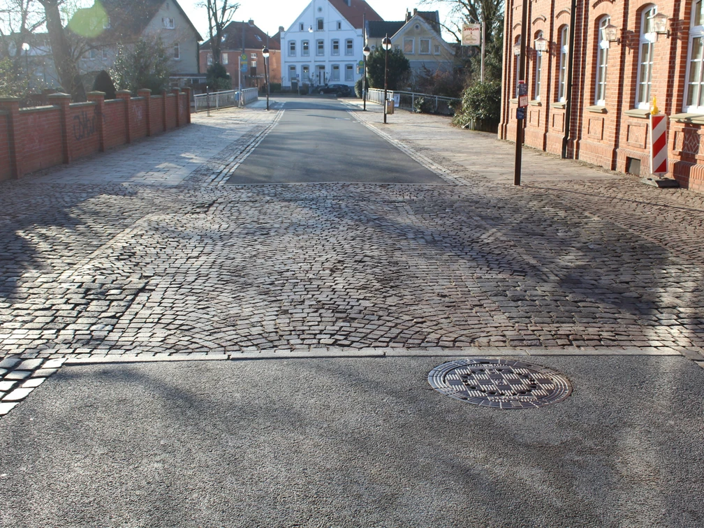 Leintor Straßenansicht mit Kopfsteinpflaster, flankiert von roten Backsteinhäusern und einem weißen Gebäude.