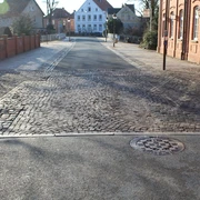 Leintor Straßenansicht mit Kopfsteinpflaster, flankiert von roten Backsteinhäusern und einem weißen Gebäude.