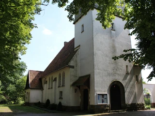 Kirche Raddestorf Kirche Raddestorf aus Backstein im gotischen Stil, umgeben von Bäumen, mit einem markanten Turm.