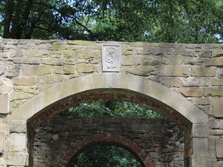 Mühlenruine Rehburg Alte Steinmauer einer Mühlenruine von Bäumen umgeben; Relief mit Wappen überbogenem Eingang.
