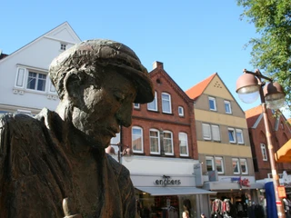 Nienburger Glasbläser Bronzestatue eines Glasbläsers in Nienburg, umrahmt von historischen Gebäuden im Hintergrund.