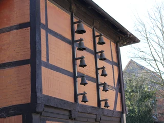 Glockenspiel Eine traditionelle Fachwerkfassade mit 10 schwarzen Glocken, die horizontal montiert sind.
