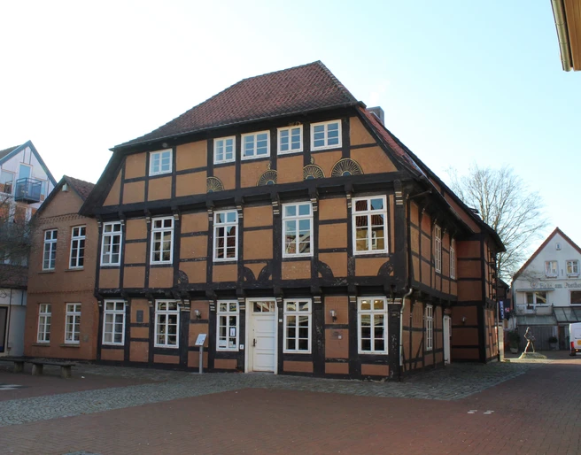 Posthof Fachwerkhaus mit rotem Ziegeldach und weißen Fensterrahmen, umgeben von gepflasterten Wegen.
