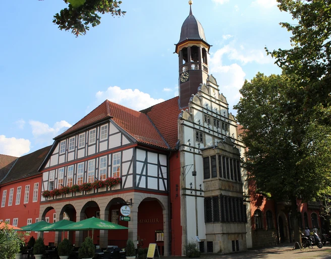Rathaus Nienburg Historisches Rathaus Nienburg mit markantem Glockenturm, Fachwerkfassade und bunter Außengastronomie.
