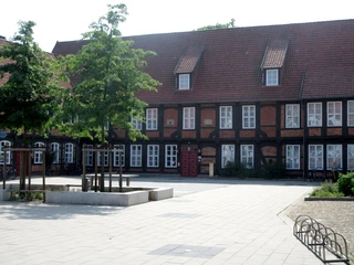 Fresenhof Historisches Fachwerkgebäude Fresenhof mit Dachschindeln, weiße Fensterrahmen, markant rotes Tor.