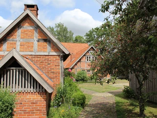 Robberts Huus Historisches Fachwerkgebäude aus Backstein in einer grünen und blühenden Gartenlandschaft.