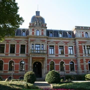 Ziegelsteinfassade mit Türmchen und Erkern, umgeben von gepflegter Gartenanlage vor Schloss Etelsen.