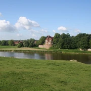 Schloss Petershagen an der Weser, umgeben von grünen Wiesen und einem klaren blauen Himmel.
