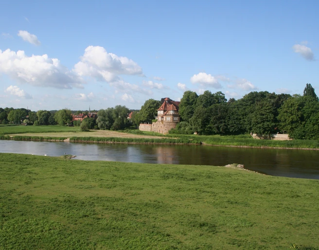 Schloss Petershagen Schloss Petershagen an der Weser, umgeben von grünen Wiesen und einem klaren blauen Himmel.