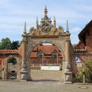 Weserrenaissance-Tor Prächtiges Tor mit figürlichen Verzierungen, flankiert von historischen Backsteinbauten.