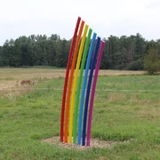 Skulptur Am Ende des Regenbogens Eine bunte Skulptur aus gebogenen Streben in Regenbogenfarben steht auf einer grünen Wiese.