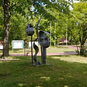 Skulptur "Beeren von Katharina Franck" Skulptur aus Metall, zeigt stilisierte Beeren in einem Park mit Bäumen und Informationstafel.