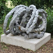 Skulptur Rolle vorwärts Steinskulptur "Rolle vorwärts" aus granitenen Segmentelementen auf Betonfundament, umgeben von Grün.