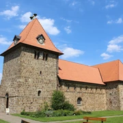 St.-Gangolf-Kirche in Wietzen Rundturm-Kirche aus Naturstein mit rotem Ziegeldach, umgeben von parkähnlicher Grünanlage.