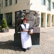 Anna - Frau vom Zigarrenmacher Eine Frau im historischen Kleid steht vor einer Skulptur eines Zigarrenmachers und einer Frau.