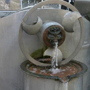 Wasserspielbrunnen Moderner Wasserspielbrunnen aus Metall, künstlerisch gestaltet, sprudelndes Wasser und Details.