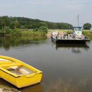Radler auf der Weserfähre Schweringen Radfahrer nutzen die Weserfähre in Schweringen, während im Vordergrund ein gelbes Boot im Wasser liegt.