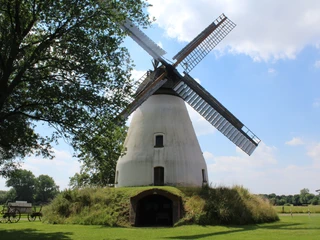 Windmühle Heimsen Historische Windmühle mit zylinderförmigem Korpus und breiten Flügeln, umgeben von Natur und Wiesen.