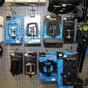 Fahrradzubehör Eine Auswahl an Fahrradzubehör, darunter Pedale und Kupplungen, auf einer grauen Lochwand montiert.