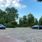 Parkplatz_MoellnerStr1_22082023_PetraRoemer.jpg Parkplatz mit Stellflächen, geparkten Autos und Hinweisschildern