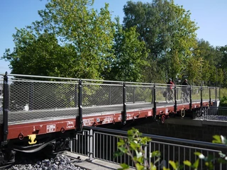 Waggonbrücke in Heiligenhaus Brücke aus alten Eisenbahnwaggons mit Gittergeländer und Radfahrern, umgeben von grünen Bäumen.