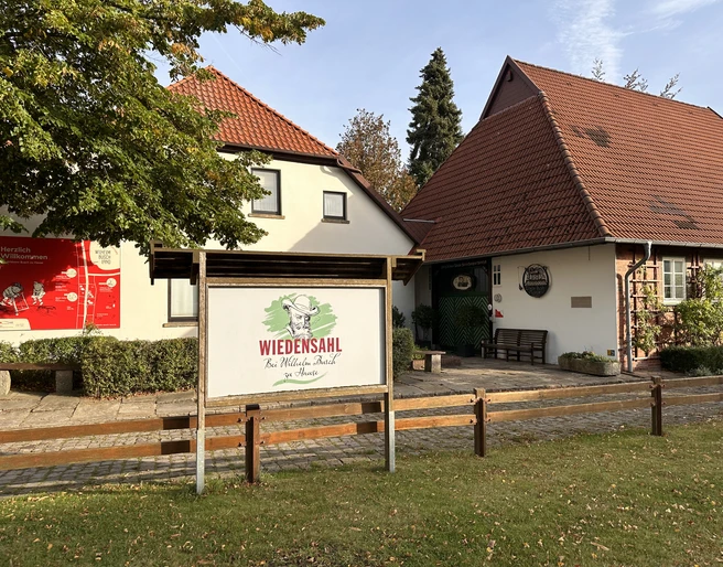 Wilhelm Busch Land Wiedensahl Wilhelm-Busch-Museum mit klassischen Giebeldächern, umgeben von Bäumen und klaren Herbsthimmel.