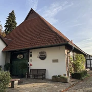 Wilhelm Busch Museum Historisches, rotes Backsteinhaus mit Satteldach, umgeben von grünem Garten, mit Eingangstür.