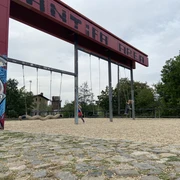 Bürgerbahnhof Plagwitz - Familienurlaub in Leipziger Industriedenkmal Zwei Schaukeln, die an einem ehemaligen Verladearm am EIngang des Bürgerbahnhofs hängen