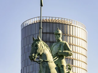 Cuirassier monument Eine Statue eines Kürassiers zu Pferd, im Hintergrund ein moderner Rundturm.A statue of a cuirassier on horseback, with a modern round tower in the background.