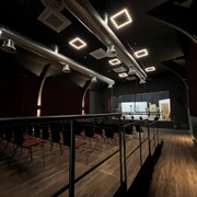 Ein moderner Veranstaltungsraum mit industriellen Lüftungsrohren und reihenweise angeordneten Sitzen.