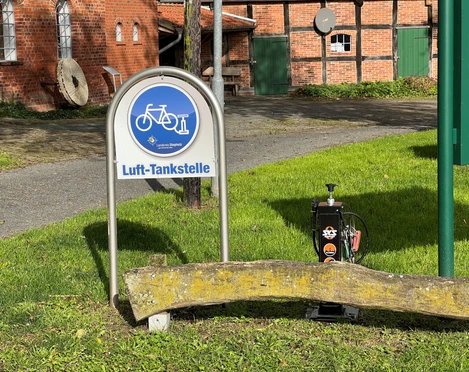 Lufttansktelle Noltesche Wassermühle Grüne Wiese mit Luft-Tankstelle vor rotbraunen Backsteingebäuden und zwei runden Mühlsteinen.