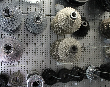 Zahnräder Fahrradzahnräder verschiedener Größen hängen an einer Lochwandtafel in einem Fahrradgeschäft.