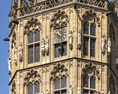Platzjabbeck Detailaufnahme des mittelalterlichen Glockenturms des Historischen Rathauses Köln mit reichhaltigem Fassadenschmuck und prominenter Uhr in der Mitte.Close-up of the medieval bell tower of Cologne's historic town hall with richly decorated façade and prominent clock in the middle.