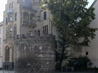 Roman tower Auf dem Bild ist der historische Römerturm in Köln zu sehen, ein gut erhaltenes Stadttor von ehemals 19 Türmen der römischen Stadtmauer, im Hintergrund das gotische Gebäude mit markanten Verzierungen und Erker, flankiert von einem üppigen Baum.The picture shows the historic Römerturm in Cologne, a well-preserved city gate of the former 19 towers of the Roman city wall, in the background the Gothic building with striking decorations and bay windows, flanked by a lush tree.