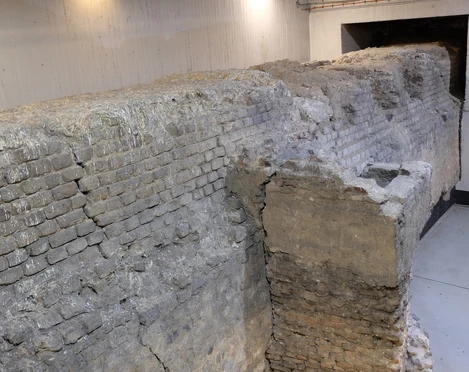 Roman city wall Das Bild zeigt eine historische Backsteinmauer in einer tiefen, beleuchteten Tiefgarage. The picture shows a historic brick wall in a deep, illuminated underground parking garage.