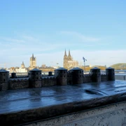 Divitia-Deutz fort Bronzemodell des römischen Kastells Divitia vor der Kulisse des Kölner Doms und der Hohenzollernbrücke am Rheinufer. Der Himmel ist klar und blau.A miniature model of Kastell Divitia with Cologne Cathedral and Hohenzollern Bridge in the background.
