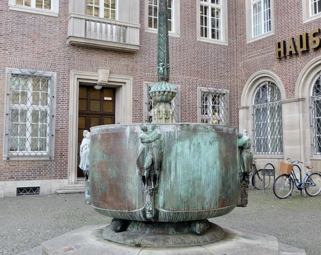 Carnival fountain Fastnachtsbrunnen vor dem historischen Gebäude in Köln, mit bogenförmigen Figuren und Brunnenbecken.Carnival fountain in front of the historic building in Cologne, with arched figures and fountain basin.