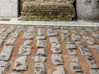Roman harbor road Römische Pflastersteine einer antiken Straße vor einer historischen Backsteinmauer in Köln.Roman paving stones from an ancient street in front of a historic brick wall in Cologne.