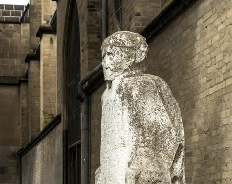 Johann Adam Schall von Bell sculpture Die Skulptur von Johann Adam Schall von Bell zeigt eine weiße Steinfigur, die mit leicht geneigtem Kopf und nach unten gerichteten Armen in einem Hof steht. Die Skulptur ist vor einer Backsteinwand platziert und strahlt eine stille Präsenz aus, die an das Erbe des Wissenschaftlers und Missionars erinnert.The sculpture by Johann Adam Schall von Bell shows a white stone figure standing in a courtyard with its head slightly tilted and arms pointing downwards. The sculpture is placed in front of a brick wall and radiates a quiet presence that recalls the legacy of the scientist and missionary.