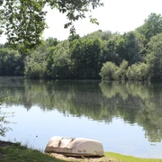 Ein ruhiger See mit umgebenden Bäumen und zwei kleinen Booten im Vordergrund bietet eine friedliche Naturkulisse.