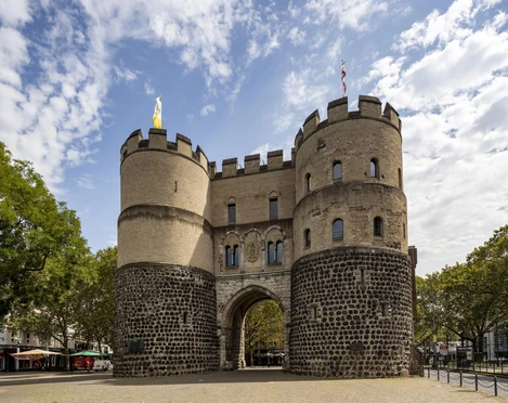 Hahnentorburg Das Bild zeigt das historische Hahnentor in Köln, eine massive Steinfestung mit zwei Rundtürmen unter blauem Himmel.The picture shows the historic Hahnentor in Cologne, a massive stone fortress with two round towers under a blue sky.