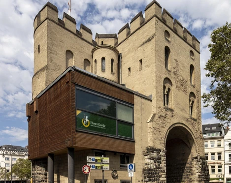 Hahnentorburg Das Hahnentor in Köln, ein mittelalterliches Stadttor aus hellem Sandstein mit drei Türmen, unter blauem Himmel.The Hahnentor in Cologne, a medieval city gate made of light-colored sandstone with three towers, under a blue sky.