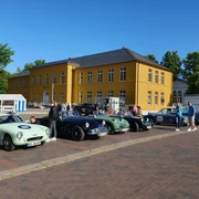 Rallye_Oldtimer.jpg Mehrere Oldtimer stehen vor dem Rathaus auf dem Parkplatz. Menschen schauen sie interessiert an