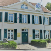 Deusser Haus in Monheim am Rhein Historisches Gebäude mit grün-weißen Fensterläden, blauer Eingangstür und Nordrhein-Westfalen-Flagge.
