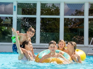 Spielende Kinder im RIFF Bad Lausick - Freizeitbad in der Leipzig Region Fünf Kinder mit Schwimmreifen spielen im Außenbecken des Freizeitbades RIFF in Bad Lausick, Familienausflug, Freizeit, Badespaß