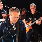 TUSH 2024.jpg Band spielt live auf Bühne der Eisenhütte, Musiker mit Gitarren und Mikrofon in konzentrierter Stimmung.
