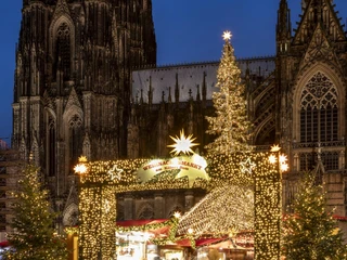 Christmas market at Cologne Cathedral Der Weihnachtsmarkt erstrahlt vor dem majestätischen Dom. Lichterketten schmücken die Stände, während festliche Tannen das Bild säumen. Ein funkelnder Weihnachtsbaum erhebt sich vor der beeindruckenden gotischen Architektur und verbreitet weihnachtlichen Glanz.The Christmas market shines in front of the majestic cathedral. Fairy lights adorn the stalls, while festive fir trees line the scene. A sparkling Christmas tree rises up in front of the impressive Gothic architecture and spreads Christmas cheer.