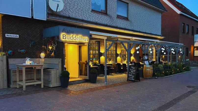 Die Außenansicht des Buddelhus, eines gemütlichen Bistros auf Borkum, bei Dämmerung.The exterior view of the Buddelhus, a cozy bistro in Borkum, at twilight.