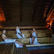 Blockhaussauna im HEIDE SPA Bad Düben - Wellness in Leipzig und Region Drei Personen mit Handtuch bedeckt, sitzen in der Blockhaussauna und entspannen im Heide Spa Bad Düben, Wellness, Entspannung, Ausflug