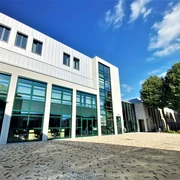 Forum Velbert Moderne Architektur des Forum Velbert mit großen Glasfassaden und angrenzenden Bäumen unter blauem Himmel.